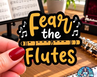 May include: A black sticker with yellow and white text that reads Fear the Flutes. The design features a yellow flute illustration in the center, surrounded by white musical notes on a black background with a thick black border.