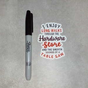 May include: A white sticker with the text "I enjoy long walks through the hardware store and the smooth sounds of a table saw" in black and red lettering.