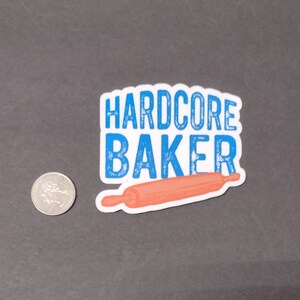 May include: A blue and white sticker with the text "HARDCORE BAKER" and a pink rolling pin.