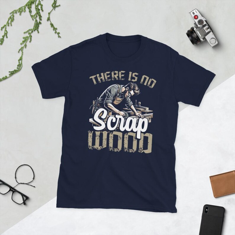 May include: A navy blue t-shirt with a graphic of a woodworker using a sander. The text on the shirt reads "There is no Scrap Wood".