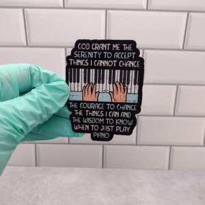 Aticker with an artistic Serenity Prayer, for piano players. Hands playing a keyboard with the text GOD GRANT ME THE SERENITY TO ACCEPT THINGS I CANNOT CHANGE, THE COURAGE TO CHANGE THE THINGS I CAN, AND THE WISDOM TO KNOW WHEN TO JUST PLAY PIANO.