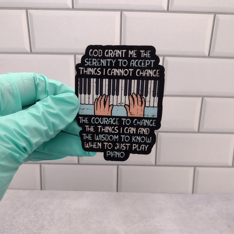 Aticker with an artistic Serenity Prayer, for piano players. Hands playing a keyboard with the text GOD GRANT ME THE SERENITY TO ACCEPT THINGS I CANNOT CHANGE, THE COURAGE TO CHANGE THE THINGS I CAN, AND THE WISDOM TO KNOW WHEN TO JUST PLAY PIANO.