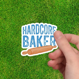May include: A blue and white sticker with the text "HARDCORE BAKER" and a drawing of a rolling pin.