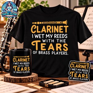 May include: A black t-shirt, a black ceramic mug, and a sticker, each featuring a yellow graphic of a clarinet and the text: CLARINET I WET MY REEDS WITH THE TEARS OF BRASS PLAYERS. The items are arranged together on a wooden surface.