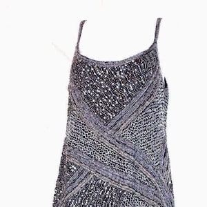May include: A dark blue and silver sleeveless dress, reaching to the knee. The bodice has a crisscross design, and the skirt is textured and patterned. The dress has thin straps.
