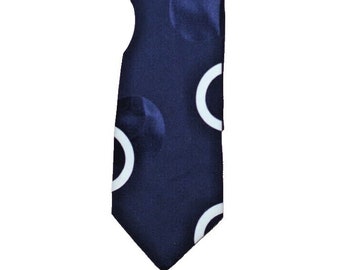 Puede incluir: Corbata azul marino con un patrón repetido de semicírculos blancos y círculos azul oscuro. La corbata es un accesorio clásico, adecuado para vestimenta formal o de negocios. La corbata está hecha de un material liso, probablemente seda.