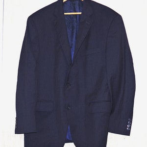 以下が含まれることがあります： 木製のハンガーに掛けられた、ネイビーブルーのピンストライプ柄のブレザー。 ブレザーは2つボタンで、ノッチドラペル、青色の裏地が付いています。 袖口にはボタンが付いています。