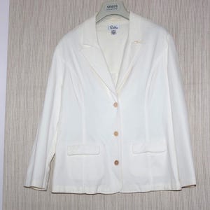 May include: Off-white blazer with a notched lapel, two front pockets, and three buttons. The blazer is hanging on a hanger. The garment has a classic design and appears to be made of a lightweight fabric. The blazer is a versatile piece of clothing.