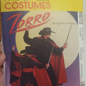 May include: McCall's Costumes sewing pattern for a Zorro costume. The pattern is for sizes 46-48, extra large. The pattern includes a black cape with a red lining, a black mask, and a sword.
