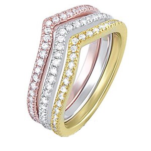 May include: Three stackable chevron rings. The rings are rose gold, silver, and gold. Each ring is encrusted with small, clear gemstones. The rings are stacked together, creating a layered effect. The rings are set against a white background.