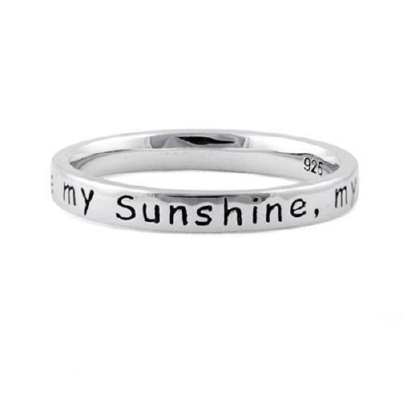 May include: A silver band ring with the inscription "You are my sunshine, my only sunshine" on the outside of the band.