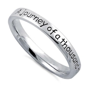 May include: A silver band ring with the inscription "A Journey of a Thousand Miles" engraved on the outside.