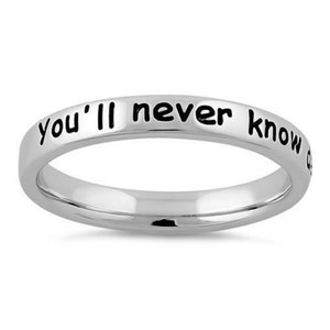 May include: A silver ring with the inscription "you'll never know" in black lettering.