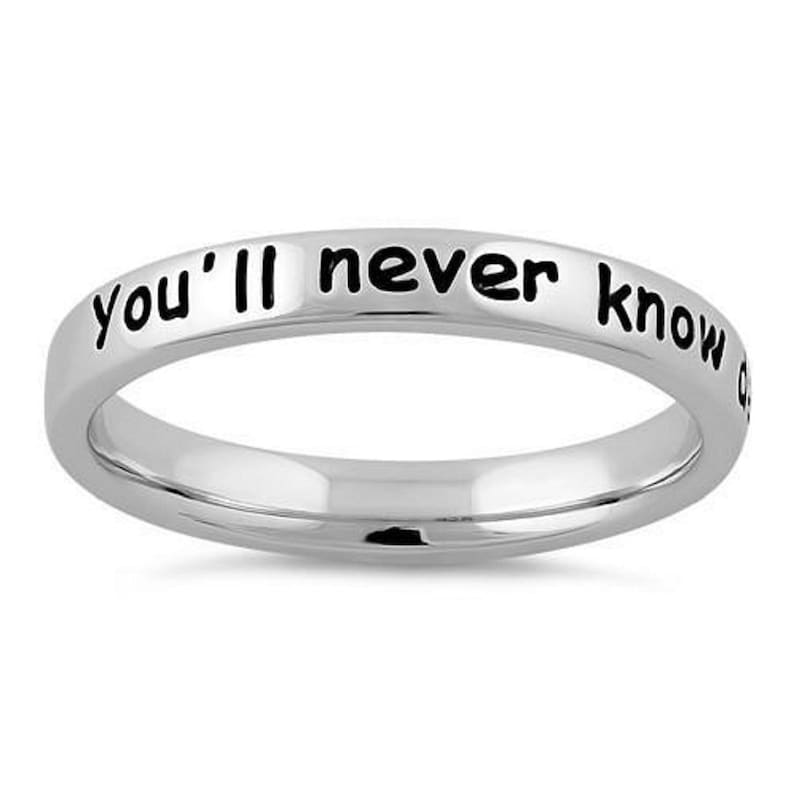 May include: A silver ring with the inscription "you'll never know" in black lettering.