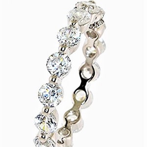 May include: A silver eternity band ring with a row of clear round cubic zirconia stones.