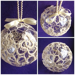 May include: A white crocheted ornament with a satin ribbon hanging from a clear glass ball.