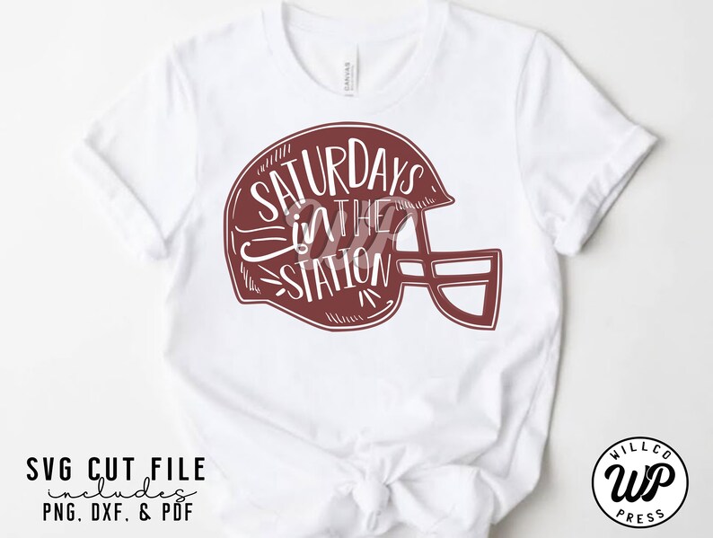 May include: White t-shirt with a maroon graphic of a football helmet with the text "Saturdays in the Station" inside the helmet.