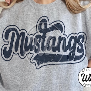 May include: A gray sweatshirt featuring the word "Mustangs" in a navy blue, retro-style font. The design has a distressed, vintage look. A circular logo with the text "Willco Press" is on the bottom right.