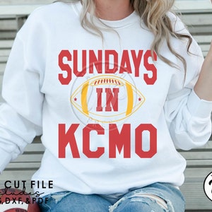 Puede incluir: Sudadera blanca con texto rojo que dice "Sundays in KCMO" con un gráfico de fútbol rojo y amarillo.