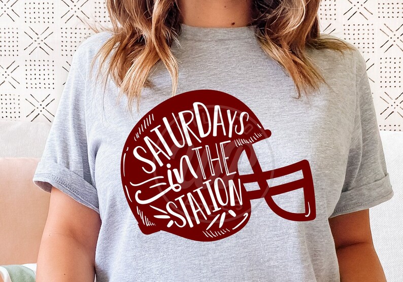May include: A gray t-shirt with a red football helmet graphic. The helmet has the text "Saturdays in the Station" written inside.