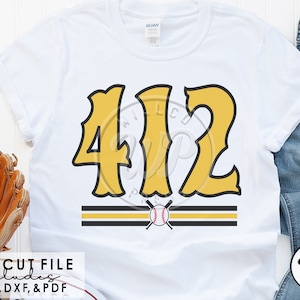 May include: A white t-shirt with a yellow number "412" in a stylized font. The number is above two black and gold stripes with a baseball and crossed bats in the center.