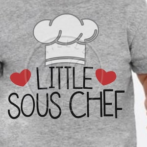 May include: A grey t-shirt with a white chef's hat graphic and the text "Little Sous Chef" with two red hearts.
