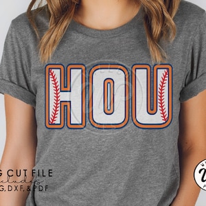 May include: A gray t-shirt with the word "HOU" in white letters outlined in orange and blue. The letters have a baseball stitch design on the sides. The text "SVG CUT FILE includes PNG, DXF, & PDF" is at the bottom left of the image.
