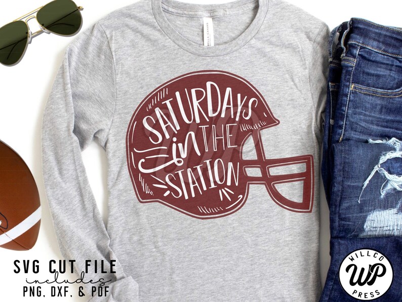 May include: A gray long-sleeve t-shirt with a maroon football helmet graphic that says "Saturdays in the Station".