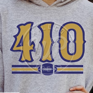 以下が含まれることがあります： グレーのフード付きスウェットシャツに、ゴールドとブルーのデザインが施され、「410」の数字とフットボールのグラフィックが描かれています。