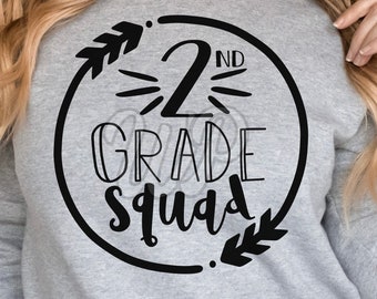 Pode incluir: Uma camisa de moletom cinza com um design circular preto que diz "2nd Grade Squad" com um design de seta preta de cada lado do texto.