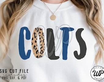 May include: White sweatshirt featuring the word "COLTS" in blue, leopard print, and black lettering. The design includes the text "SVG CUT FILE includes PNG, DXF, & PDF" and a circular logo with the text "WILLCO WP PRESS".