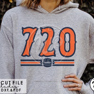 May include: A gray hoodie with a large orange and blue number "720" printed on the front. The number is in a vintage style font with a football graphic below it. The text "SVG CUT FILE includes PNG, DXF, & PDF" is printed below the graphic.