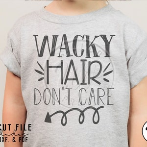 May include: A gray t-shirt with the text "WACKY HAIR DON'T CARE" in black. The text is in a handwritten style with a whimsical arrow pointing to the right.