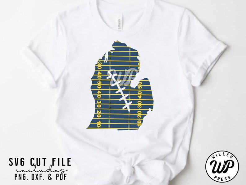 May include: A white t-shirt with a blue and yellow Michigan state outline design. The outline is shaped like a football field with yard lines and a football player graphic. The text "SVG CUT FILE includes PNG, DXF, & PDF" is at the bottom of the image.
