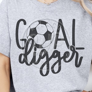 May include: Gray t-shirt with a black soccer ball graphic and the text "Goal Digger" in a black script font.