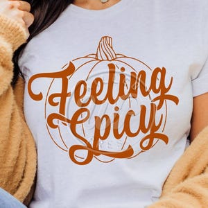 May include: White t-shirt with an orange pumpkin graphic and the text "Feeling Spicy" in a decorative font.