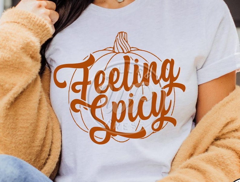 May include: White t-shirt with an orange pumpkin graphic and the text "Feeling Spicy" in a decorative font.