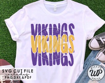 May include: White t-shirt with the word "VIKINGS" in purple and gold block letters. The shirt includes the text "SVG CUT FILE includes PNG, DXF, & PDF". A football and sneakers are in the background.