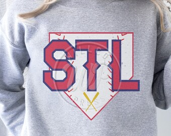 Könnte beinhalten: Grauer Sweatshirt mit einem roten, weißen und blauen Baseball-Diamanten-Motiv. Das Motiv zeigt die Buchstaben "STL" in einer Vintage-Schriftart. Zwei gekreuzte Baseballschläger befinden sich unten im Diamanten.