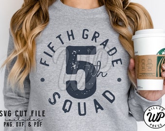 May include: A gray sweatshirt with the text "FIFTH GRADE 5th SQUAD" in black. The number 5 is distressed and has a white outline. The sweatshirt is being worn by a person holding a coffee cup.