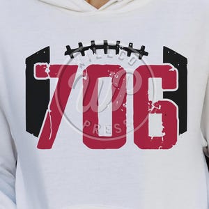 May include: White hoodie with a red and black graphic of the number 706 inside a football shape. The graphic has a distressed look.