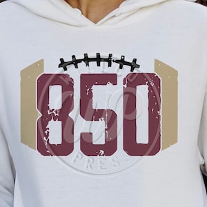 May include: White hoodie with a maroon and tan graphic of a football with the number 850 inside.