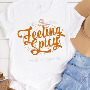 May include: White t-shirt with an orange pumpkin graphic and the text "Feeling Spicy".
