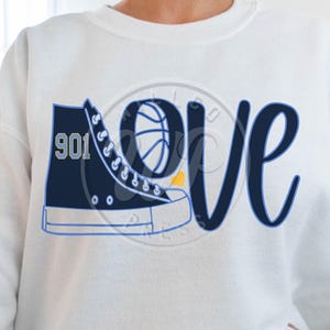 May include: White sweatshirt with a blue and yellow graphic design featuring a basketball, a sneaker with the number "901" on it, and the word "love".