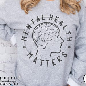 May include: Gray sweatshirt with a black graphic design that says "Mental Health Matters" and includes a stylized brain with a face. The graphic is in a circle.