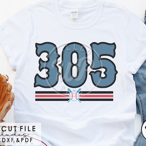 Puede incluir: Una camiseta blanca con el número "305" en azul en una fuente de béisbol vintage. El número está sobre dos rayas rojas y negras con una pelota de béisbol y bates cruzados en el centro.