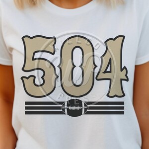 May include: White t-shirt with a brown and black design featuring the number "504" and a football graphic.