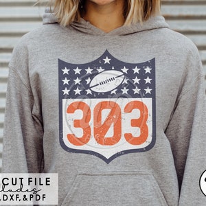 May include: A gray hoodie with a vintage-style football jersey design featuring a shield with stars and the number 303. The shield has a distressed look and the number is in orange.
