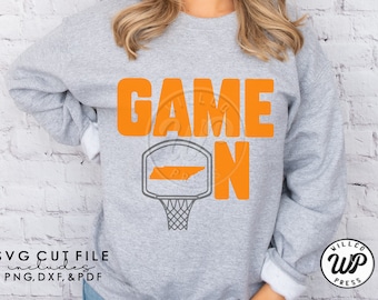 May include: A gray sweatshirt with the text "GAME ON" in orange letters. A basketball hoop with the outline of the state of Tennessee is in the center of the text.