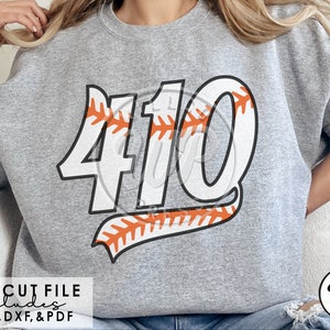 May include: A gray sweatshirt with a white baseball-themed design featuring the number "410" with orange stitching. The design is on the front of the sweatshirt.